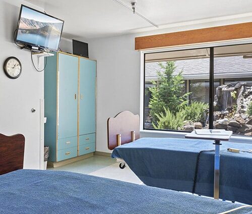 A patient's shared room with TV and window at Ashland Post Acute