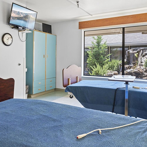 A patient's shared room with TV and window at Ashland Post Acute