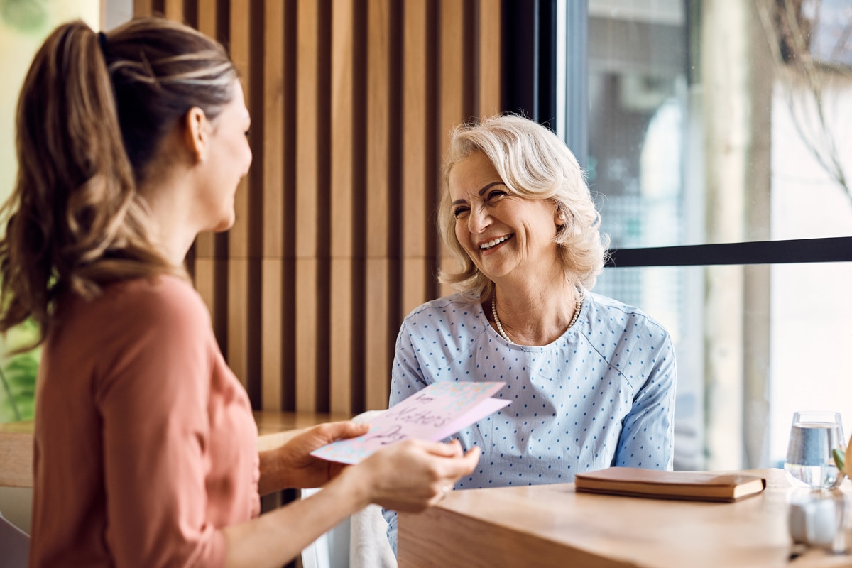 Woman holding card smiling with older woman