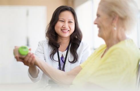 female physical therapist helping female senior curl dumbbell